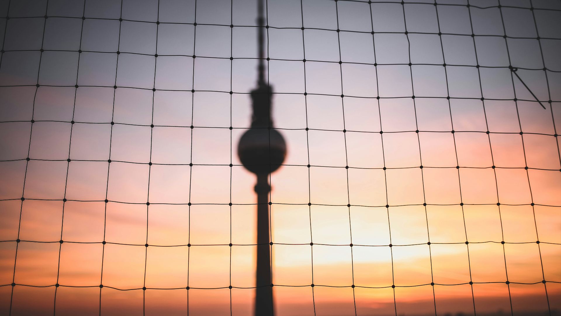 silhouette photo of hanging decor behind chain link fence at golden hour