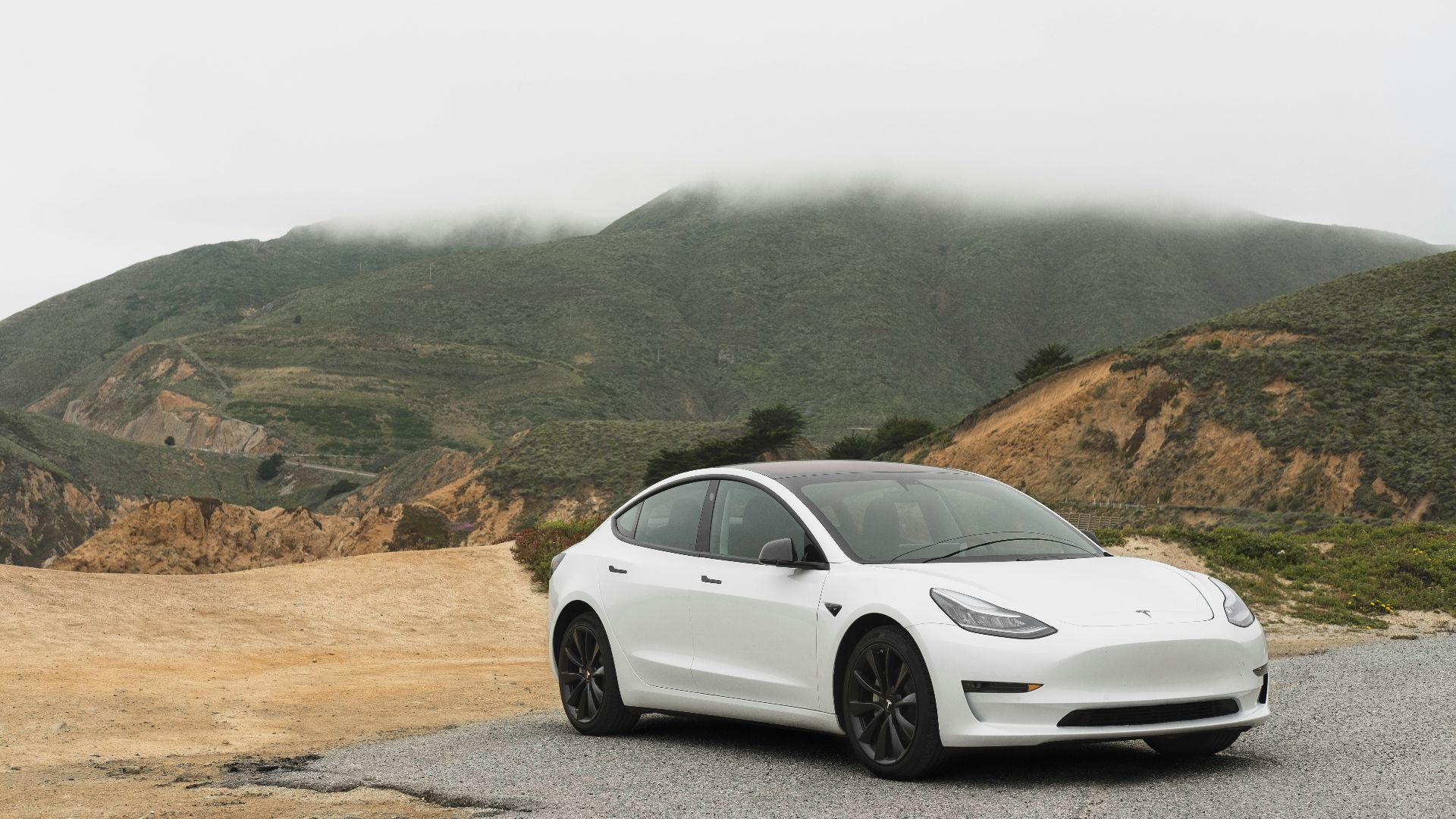 white sedan parked beside mountain during daytime