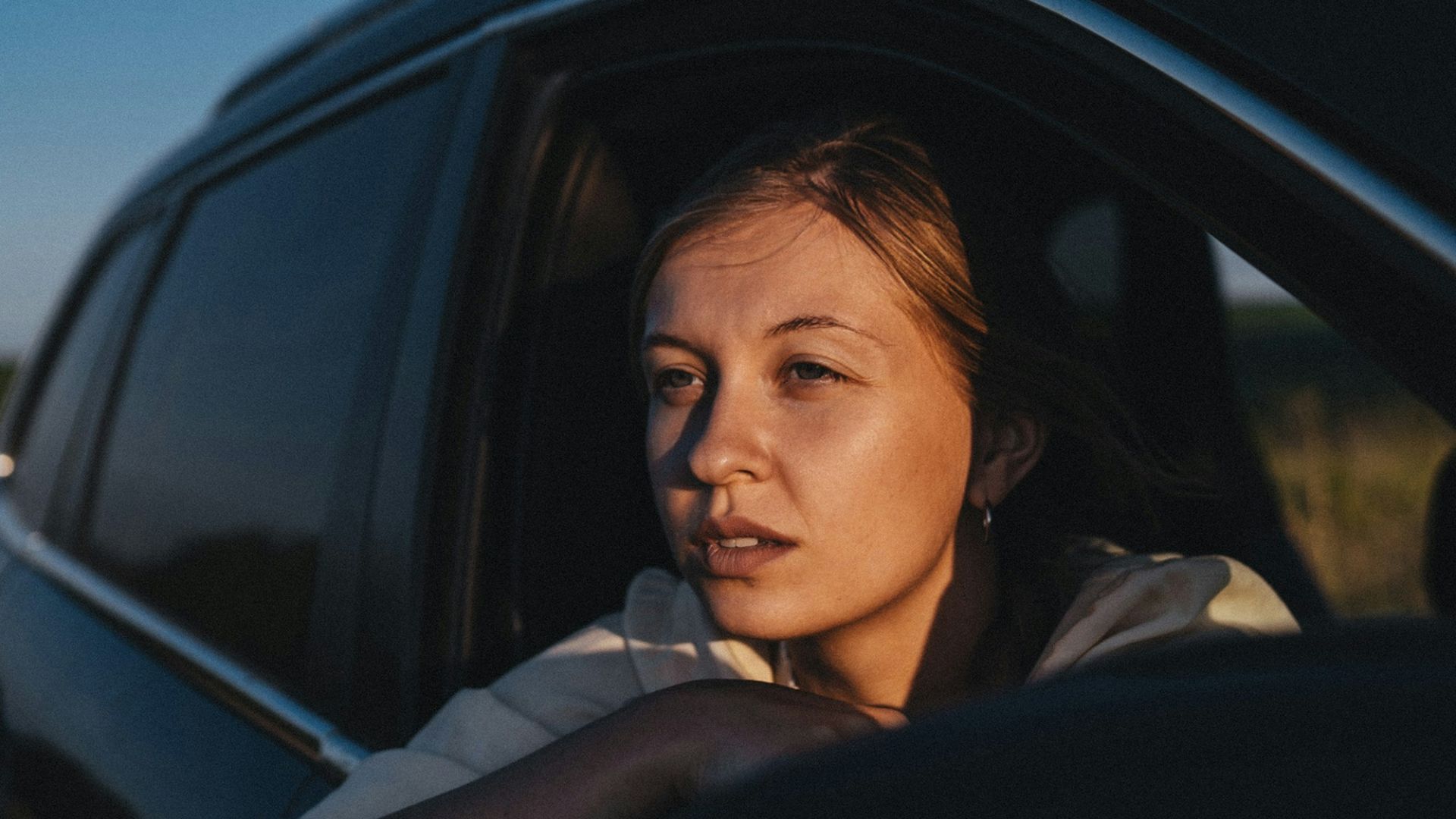 a woman sitting in a car looking out the window