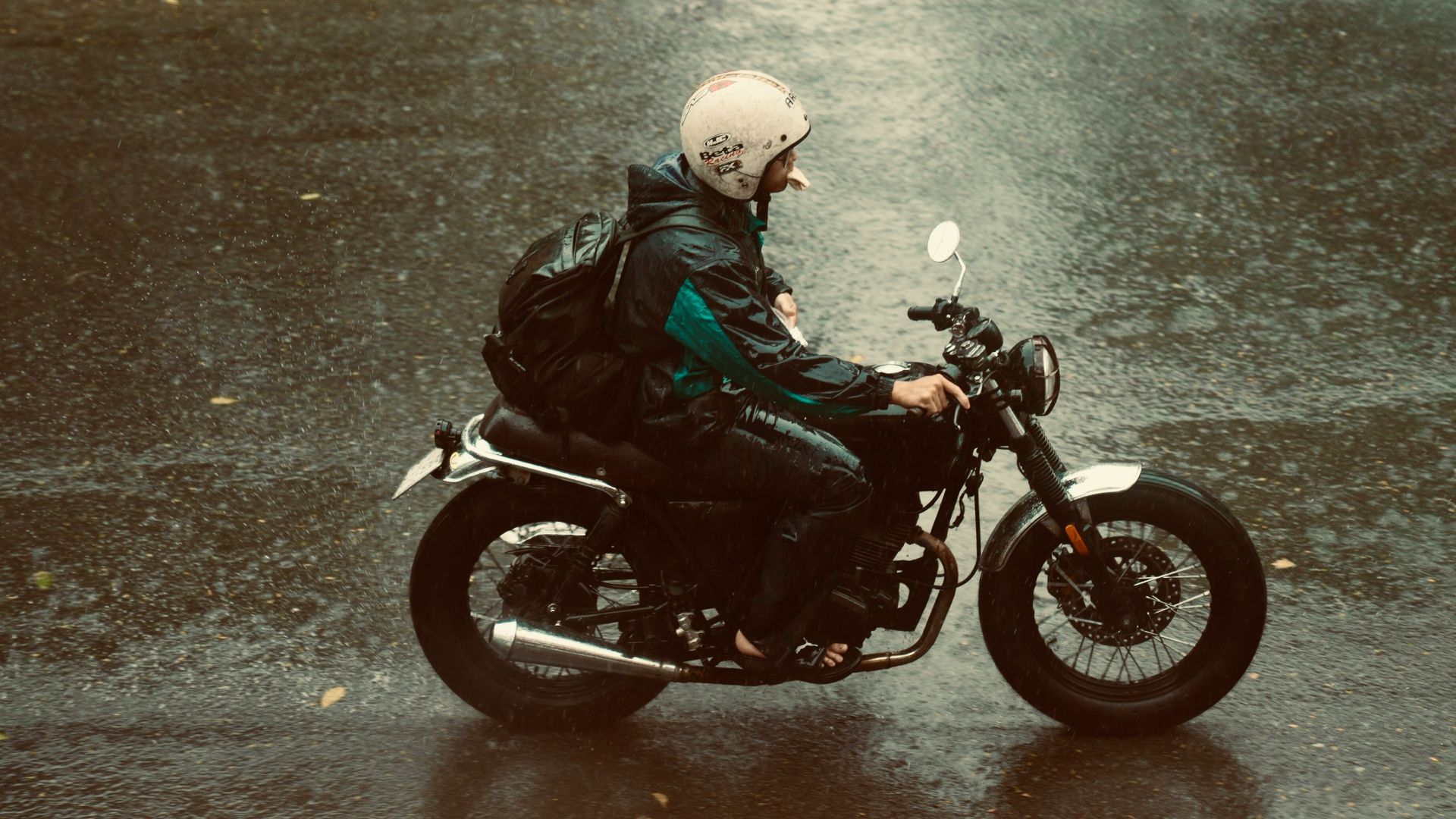 a man riding a motorcycle down a rain soaked street