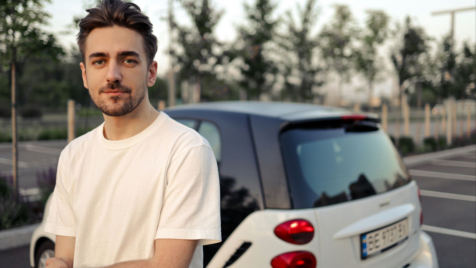 man in white crew neck t-shirt standing beside white car during daytime