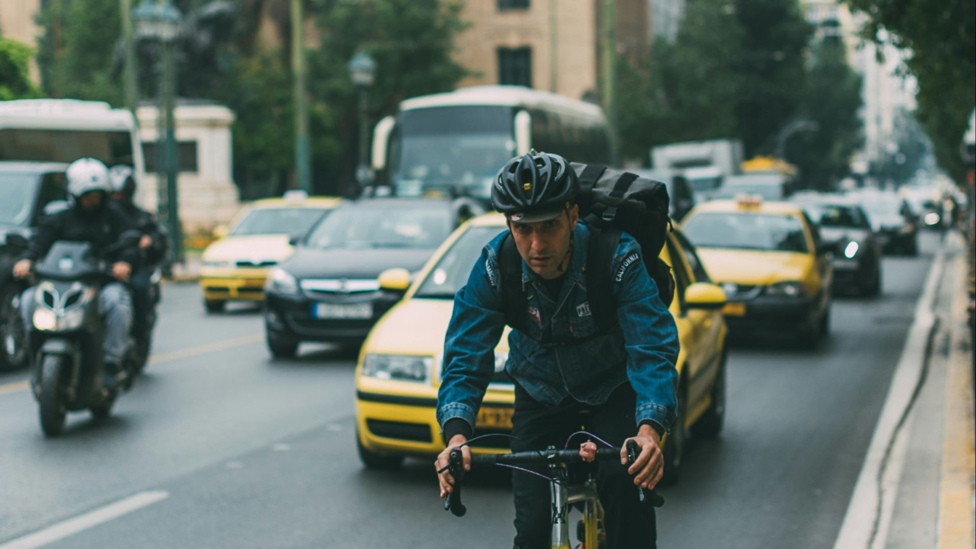 man riding bicycle on a road with cars during daytime