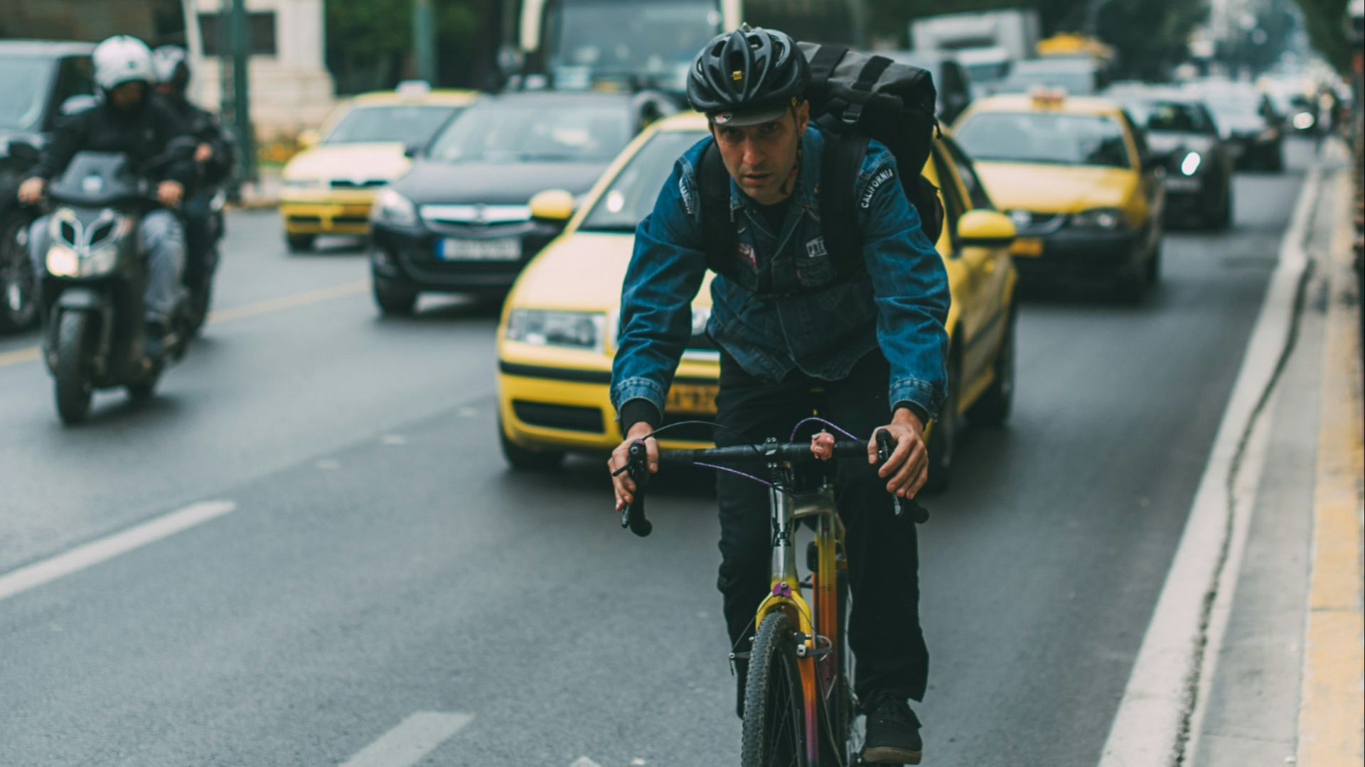 man riding bicycle on a road with cars during daytime