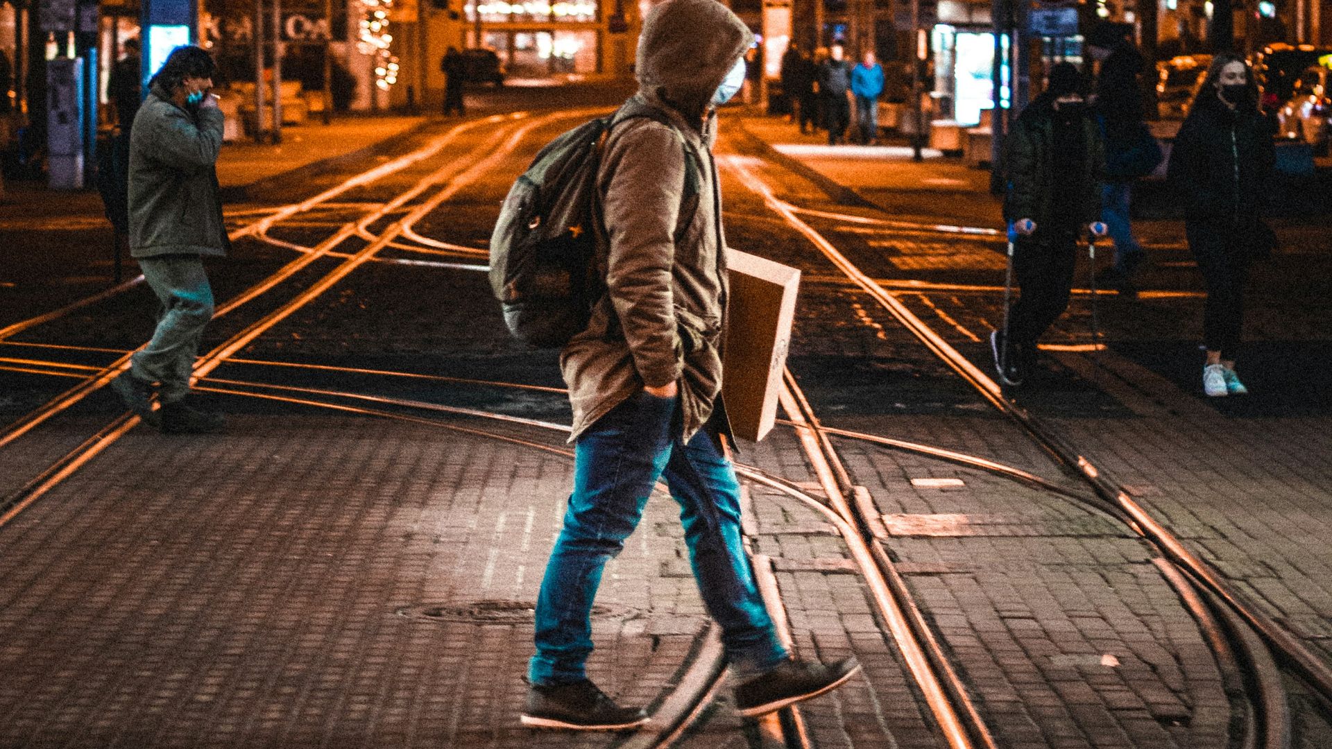 woman in gray jacket walking on sidewalk during night time