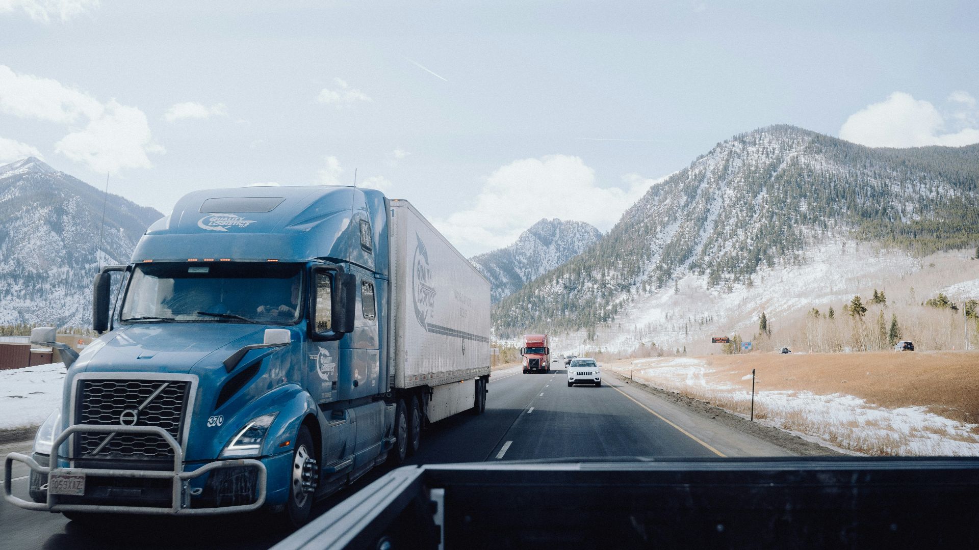 a blue semi truck driving down a mountain road