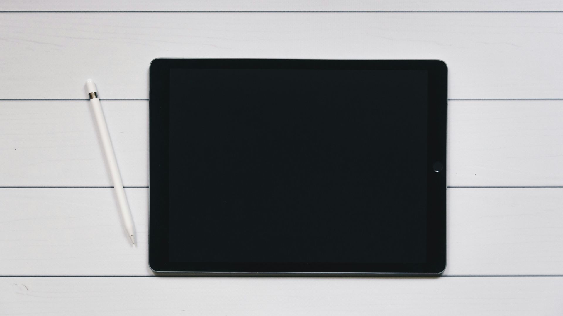 space gray iPad with Apple Pencil with white and black pinstriped background