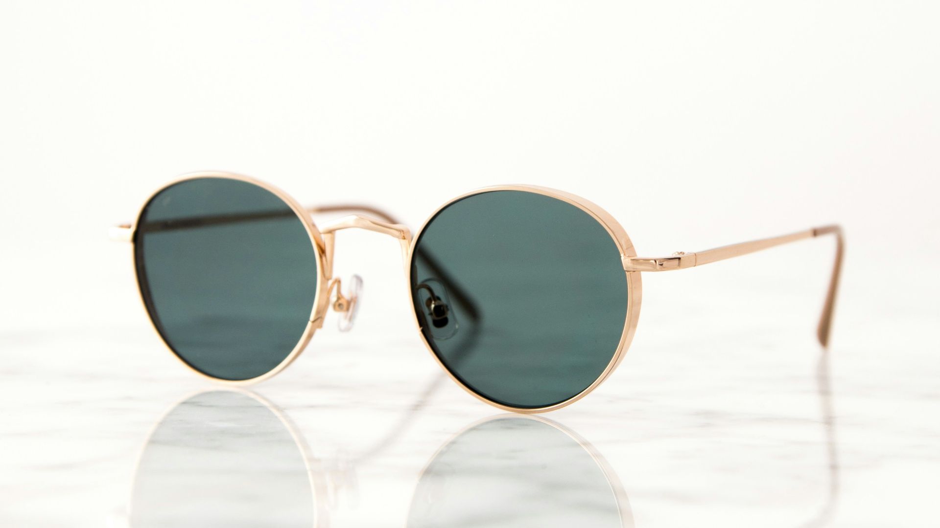 gold-colored framed hippie sunglasses on white surface