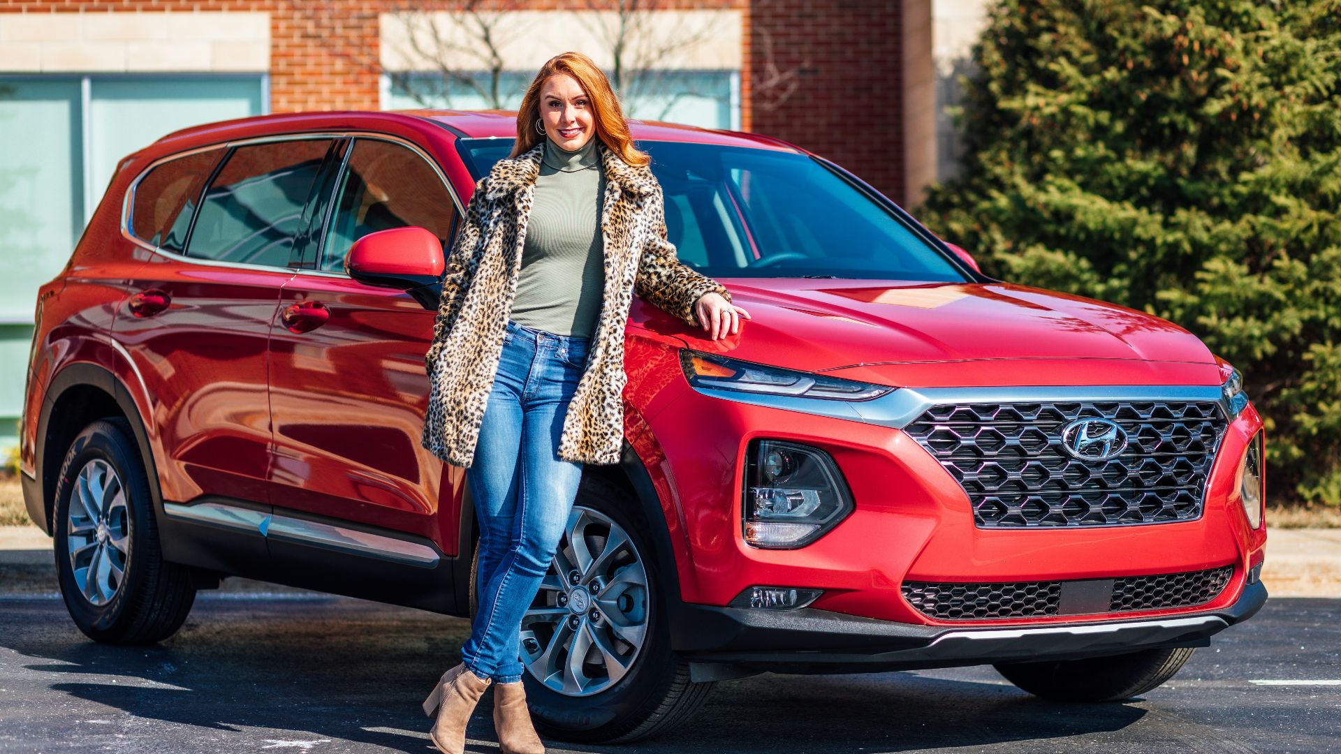 woman in white and black scarf and blue denim jeans standing beside red mercedes benz car