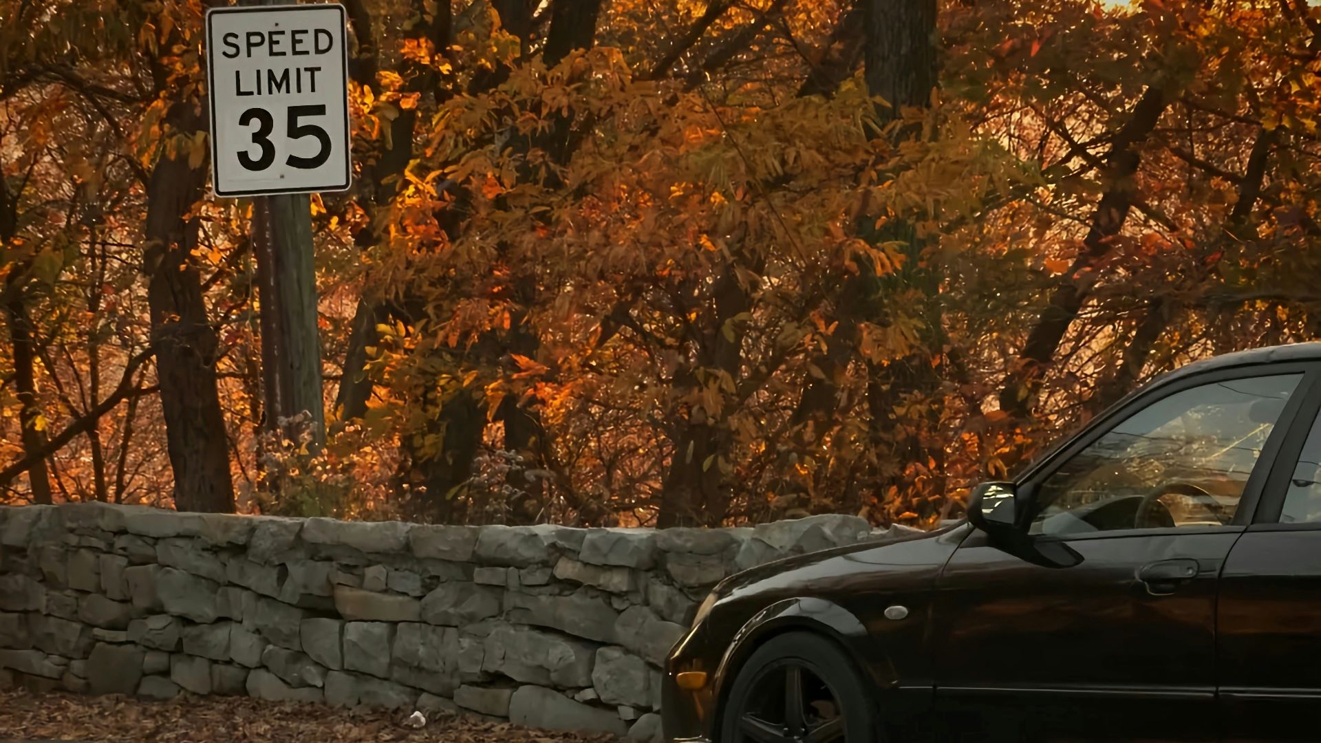 a black car parked next to a stone wall