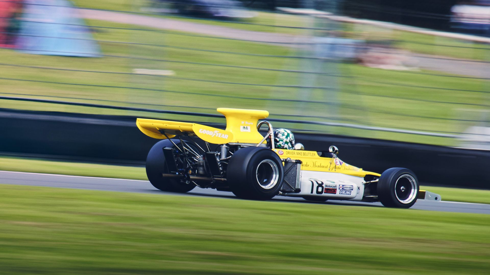 a yellow race car driving down a race track