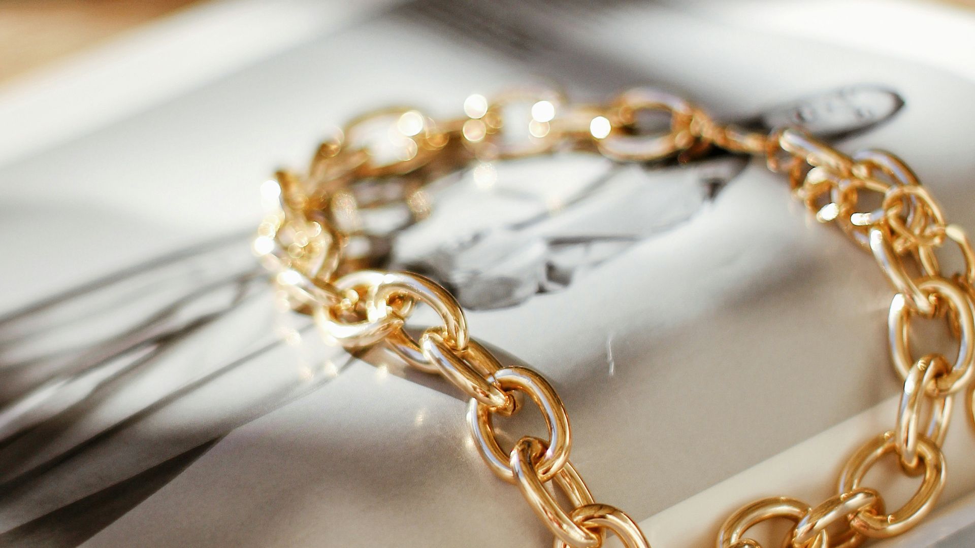 a gold chain bracelet sitting on top of a magazine