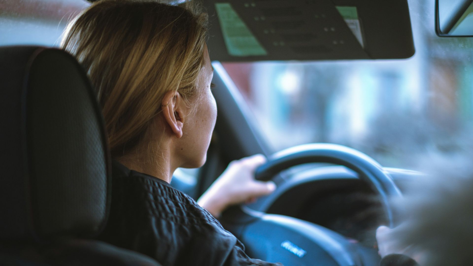 a woman sitting in a car with a steering wheel