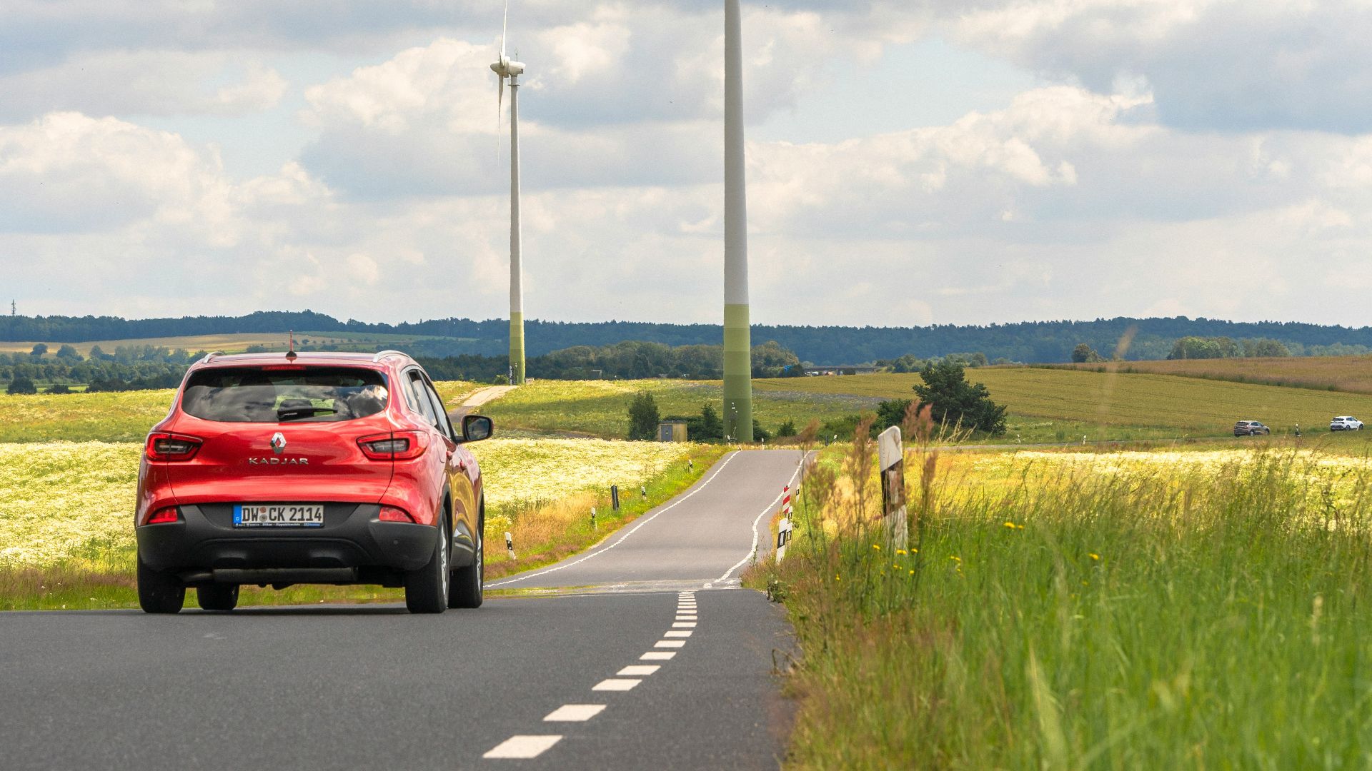 A red car driving down a country road