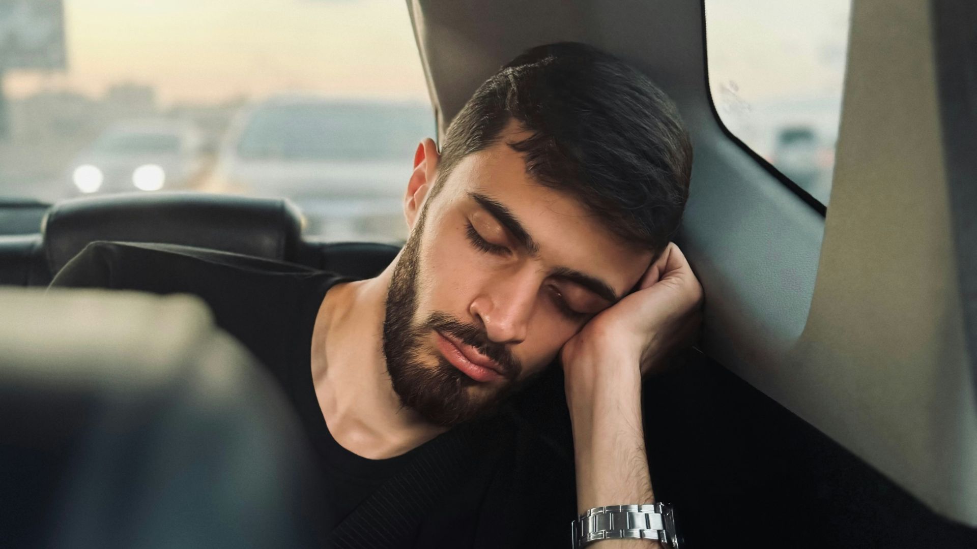 A man sitting in the back seat of a car