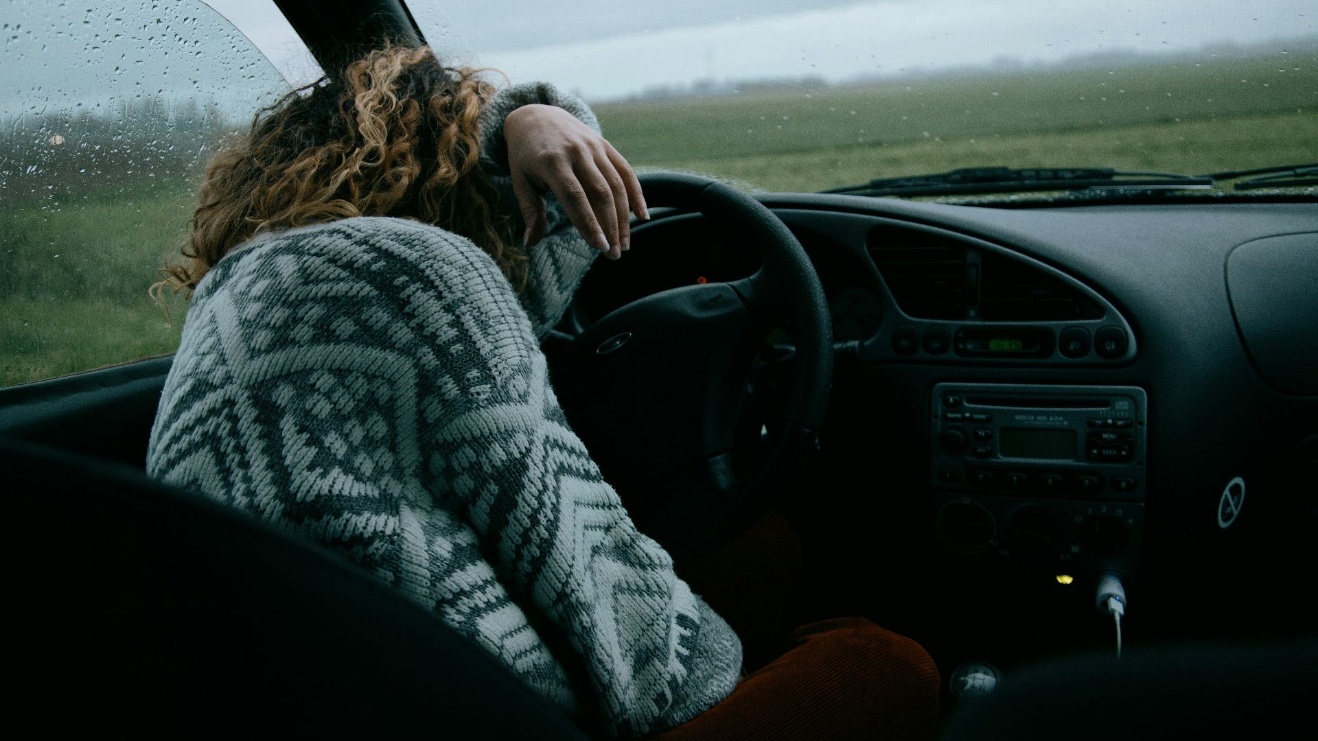 person in gray and white sweater driving car