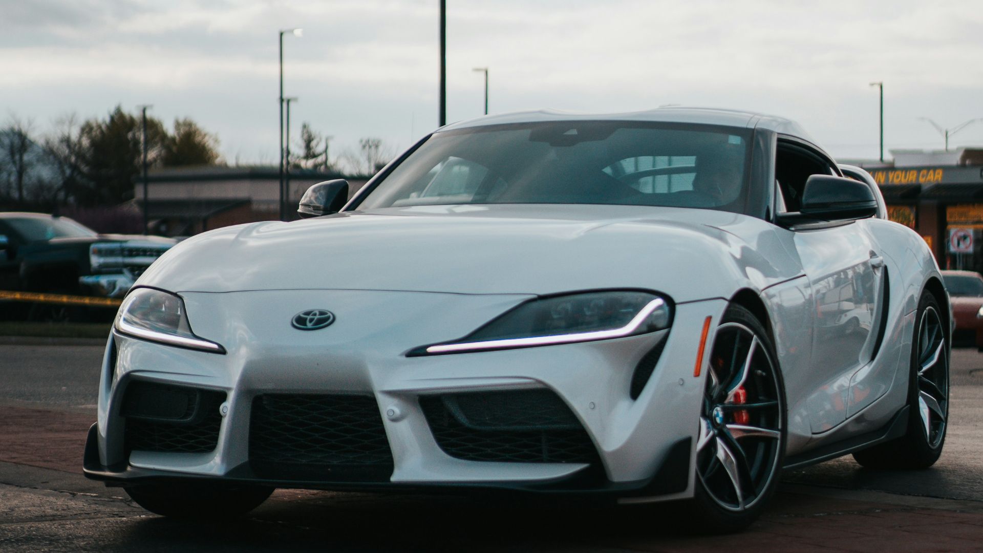 A white sports car is parked in a parking lot.