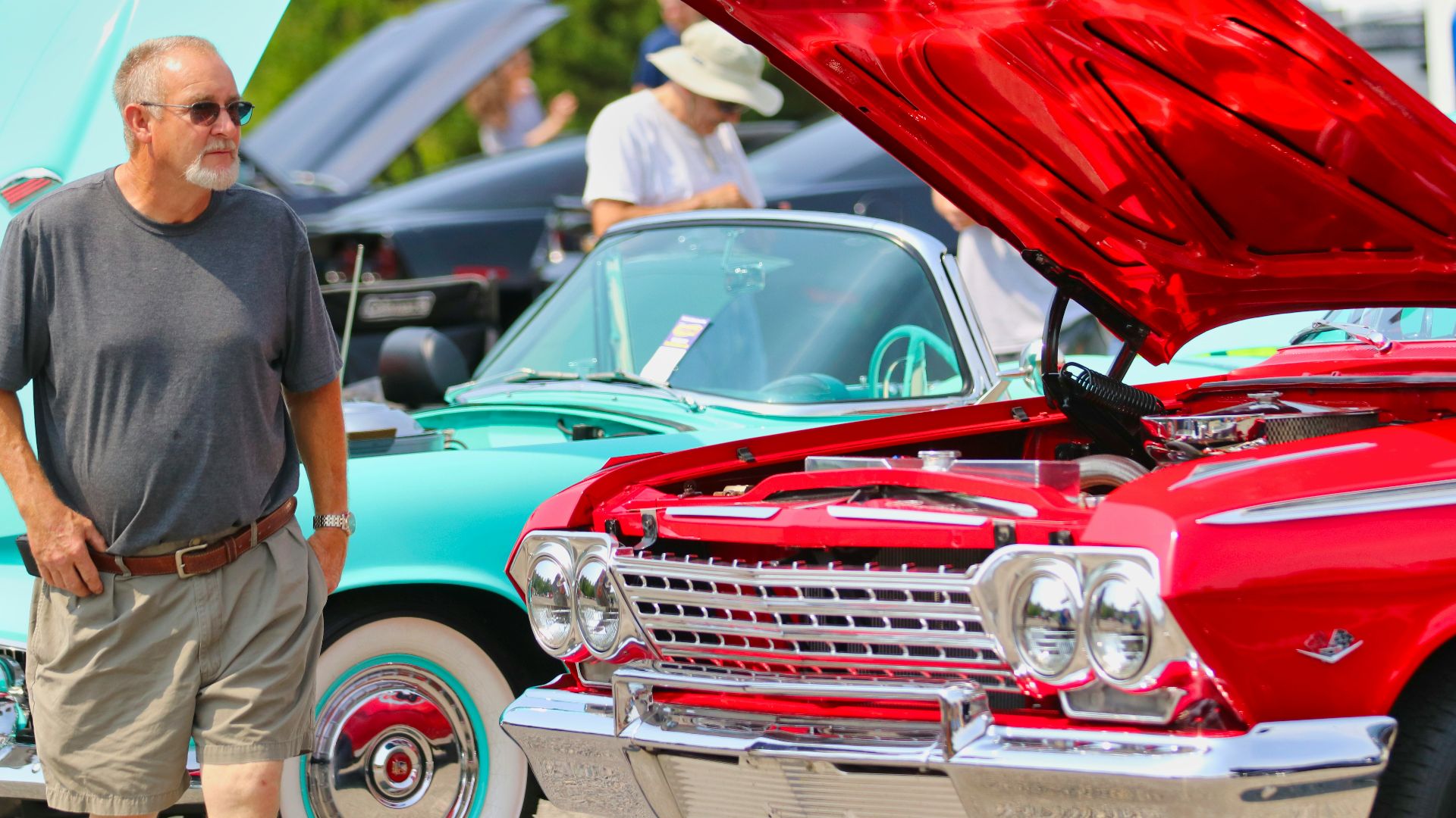 man in black t-shirt standing beside red car during daytime