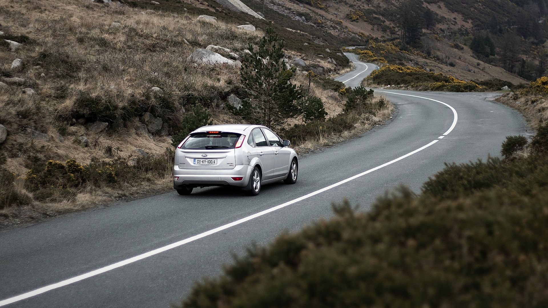 photography of moving silver sedan on road