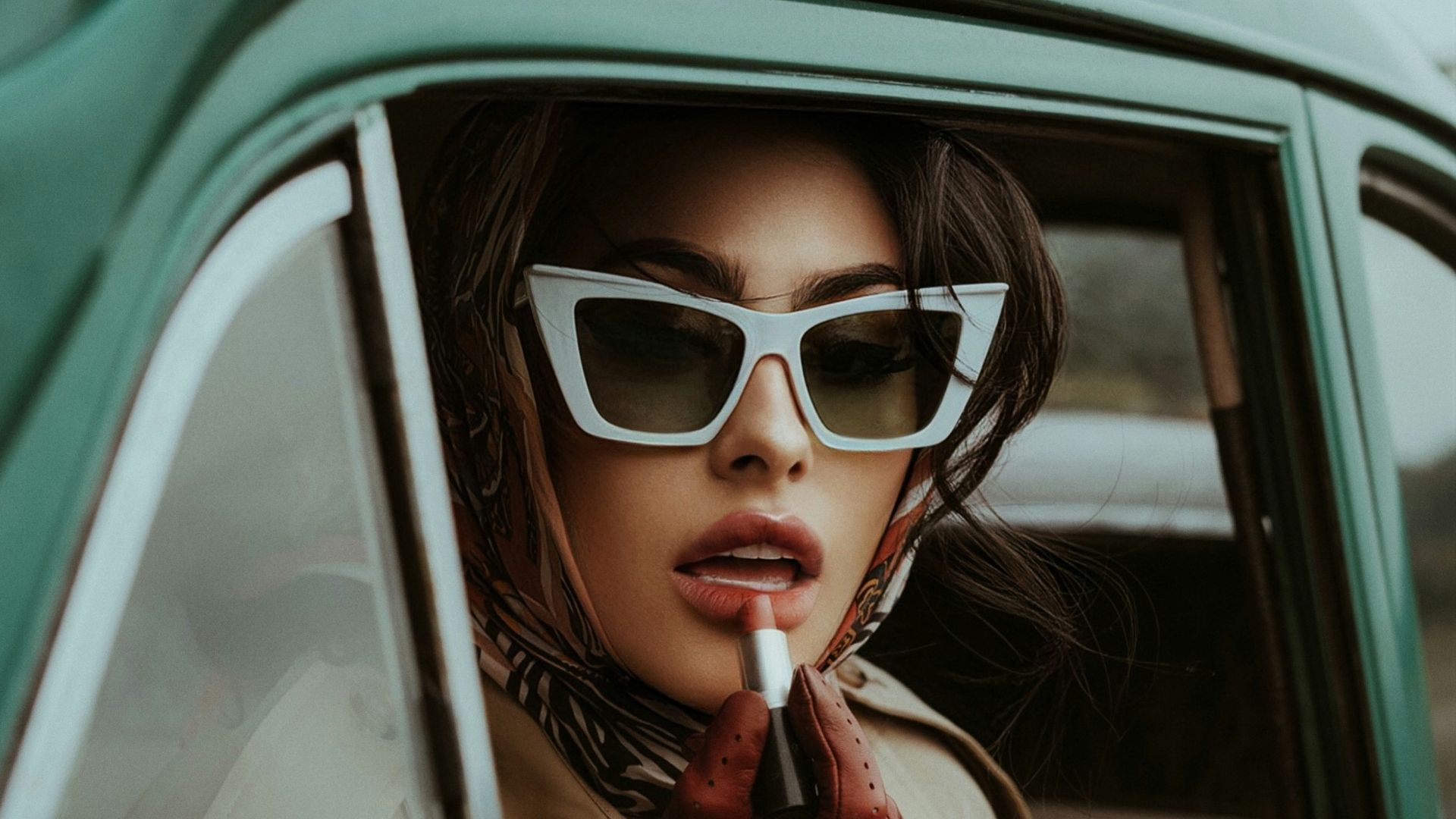 a woman in sunglasses smoking a cigarette in a car