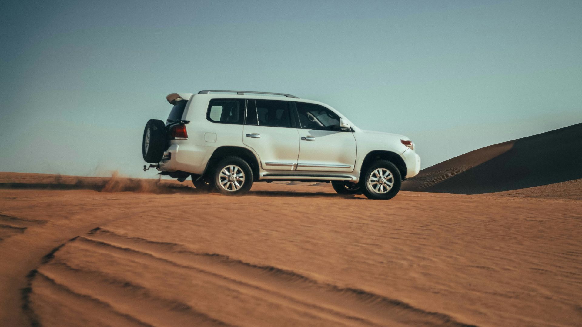 a white suv driving through the desert on a sunny day