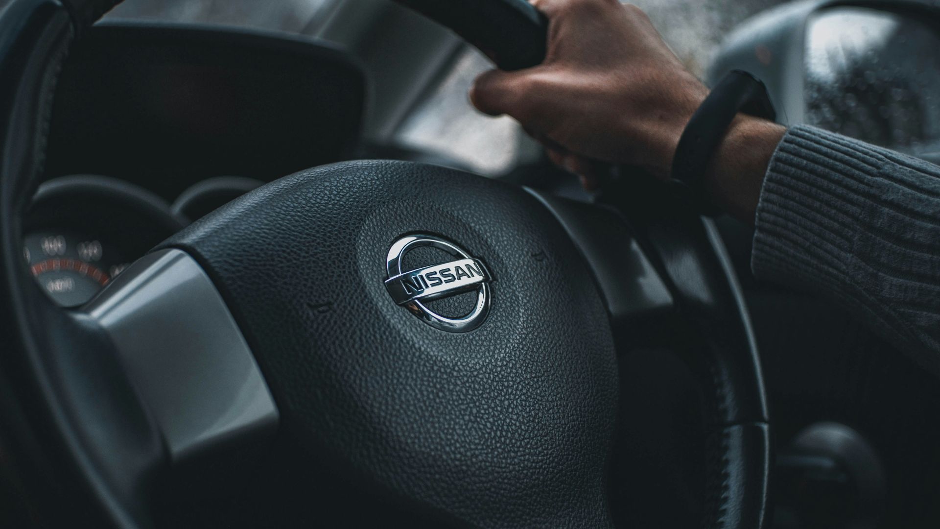 person holding black nissan steering wheel