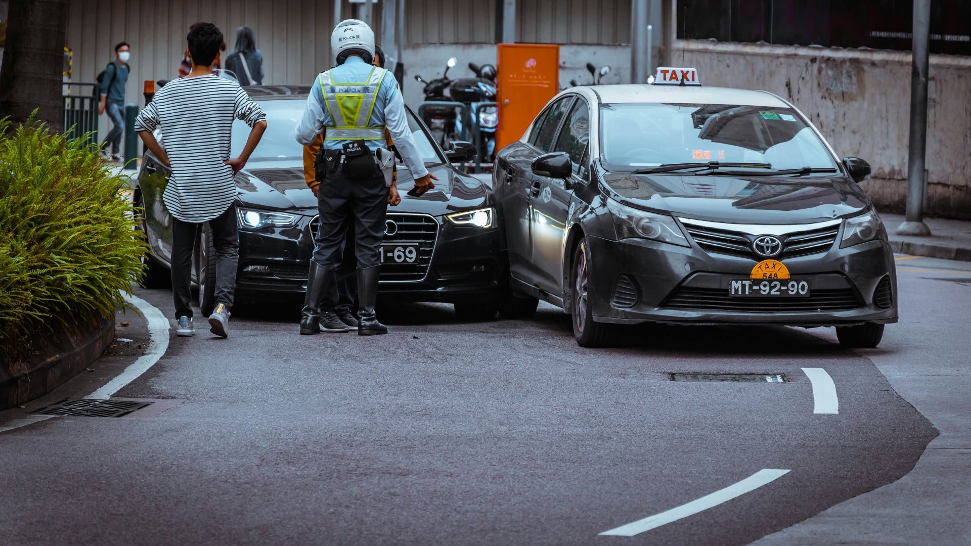 man in white and black stripe shirt and black pants standing beside black car during daytime