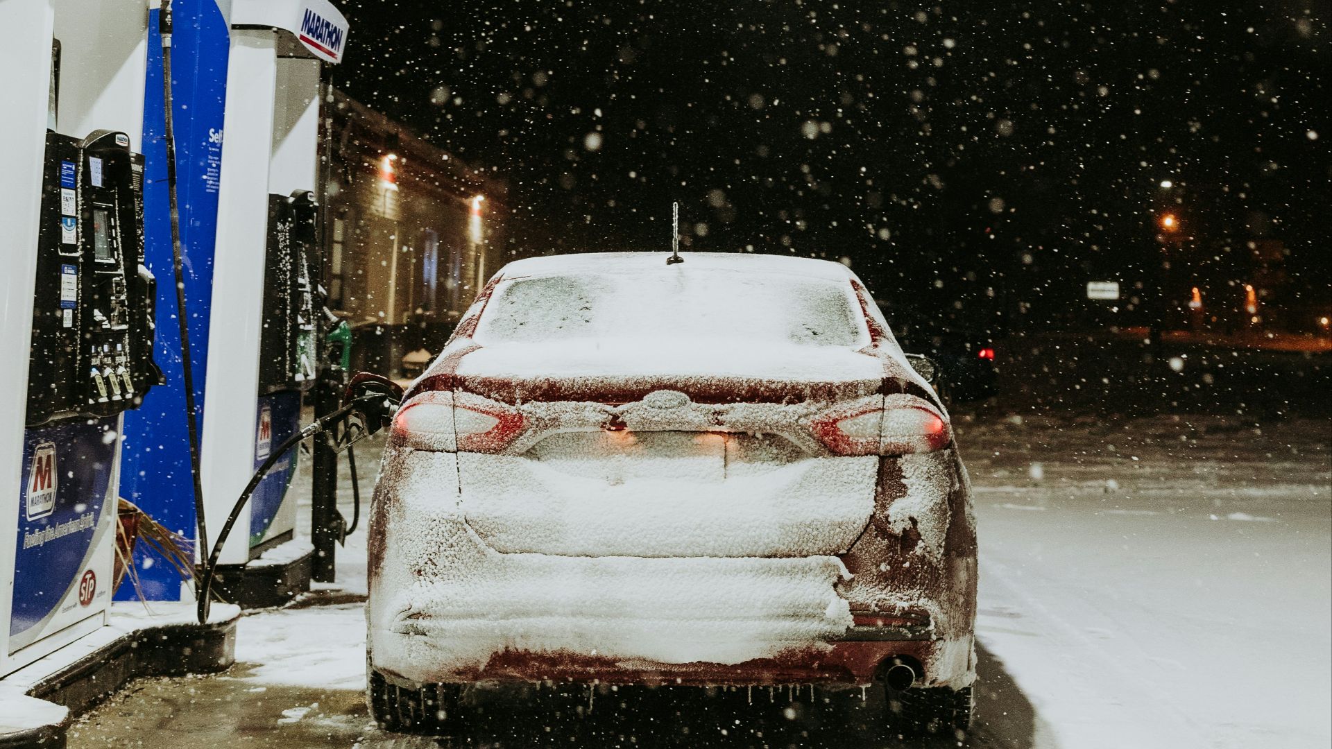 a car is parked at a gas station in the snow