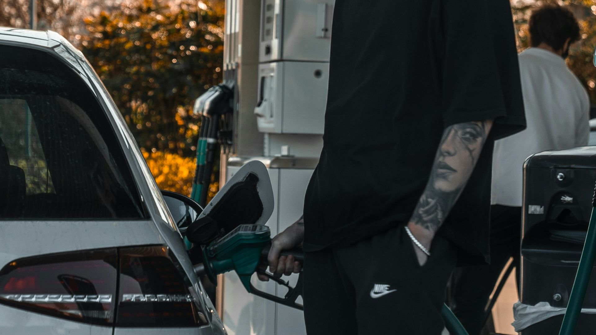 man in black suit standing beside red car during daytime