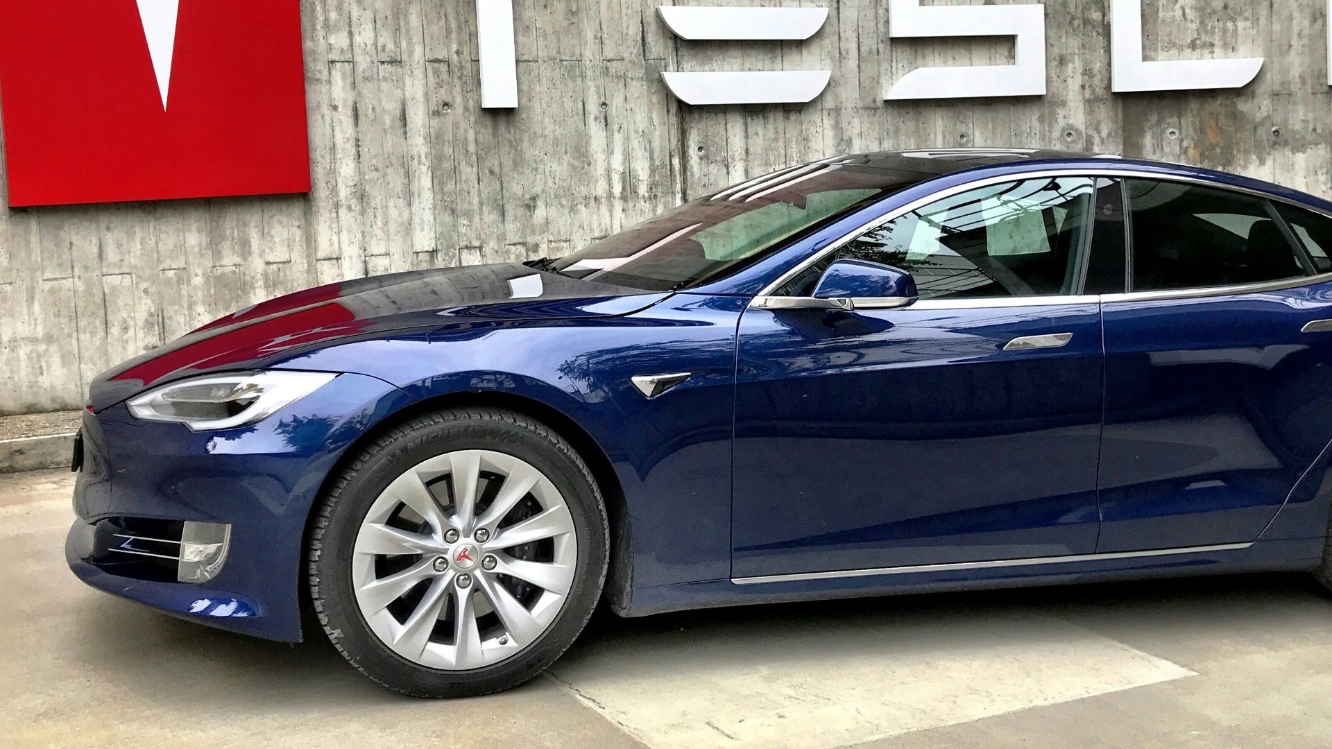 blue coupe parked beside white wall