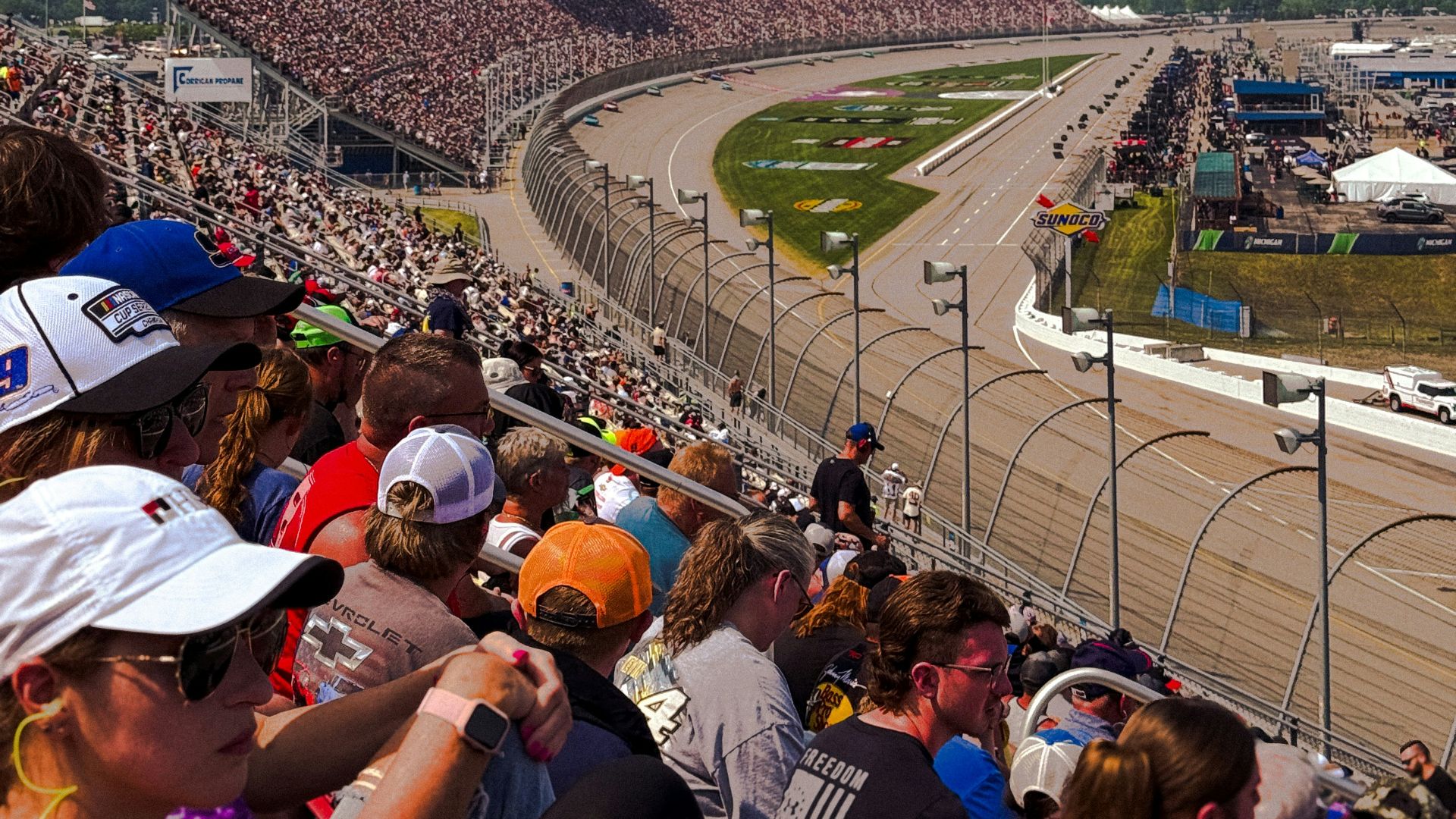 Race fans watch a car race from the stands.