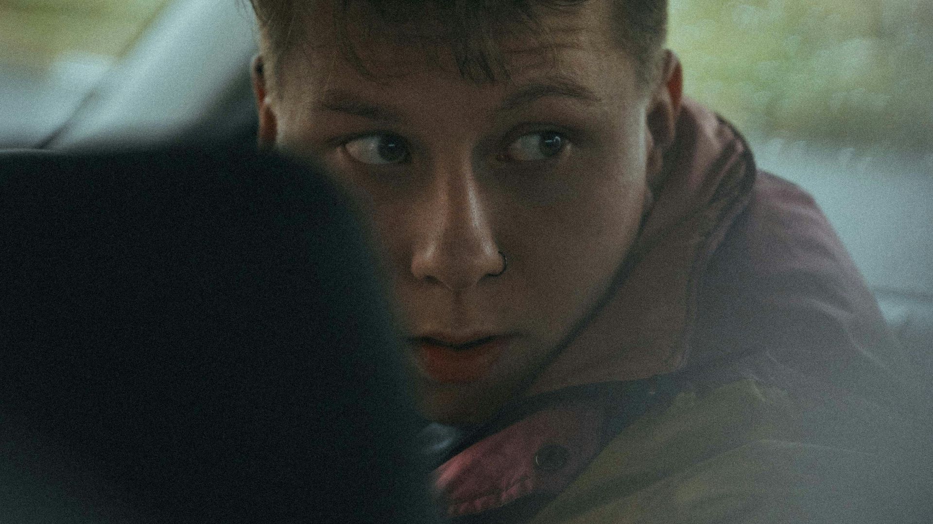 man in brown jacket sitting on car seat