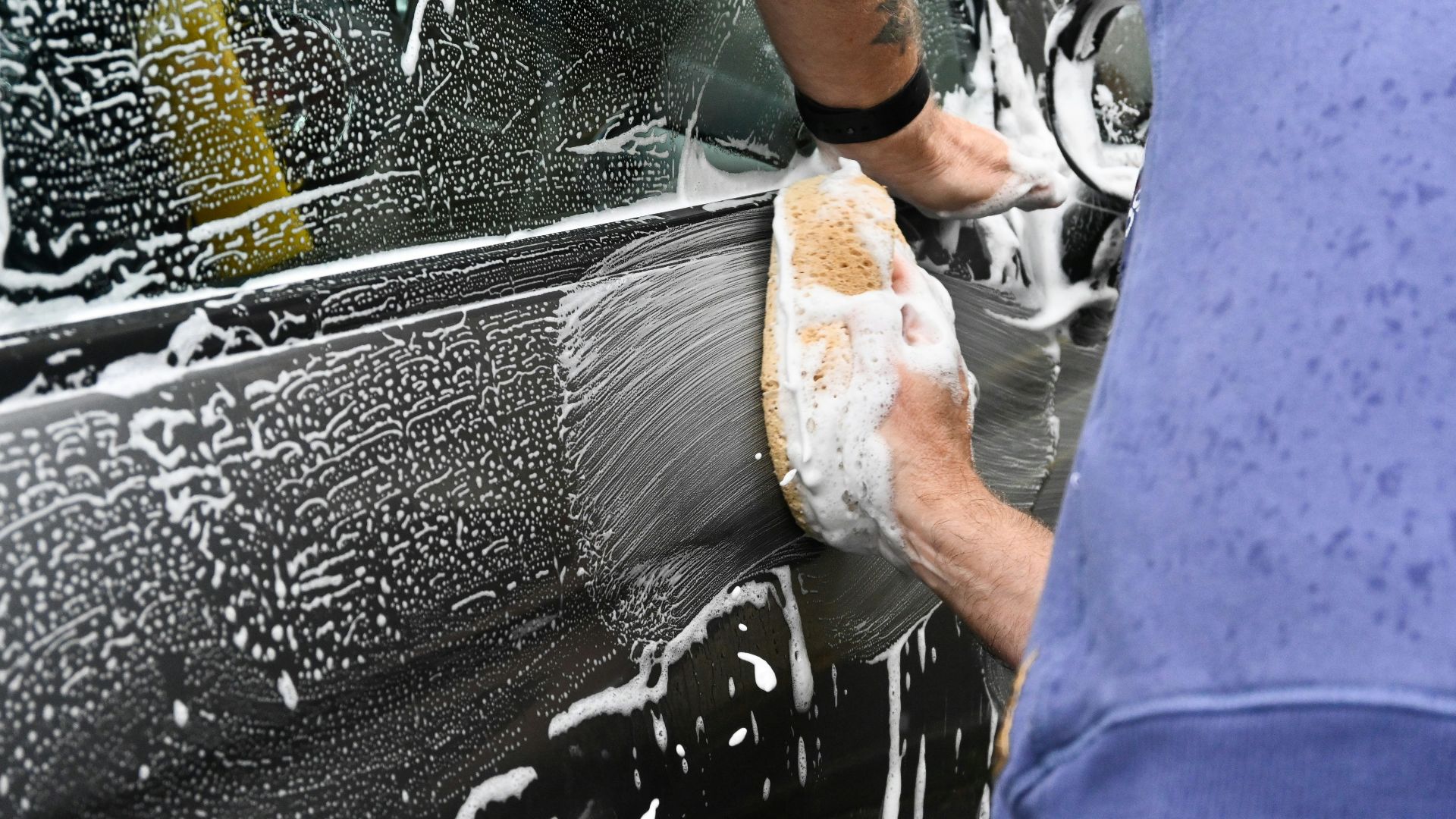 a man washing a car with a sponge