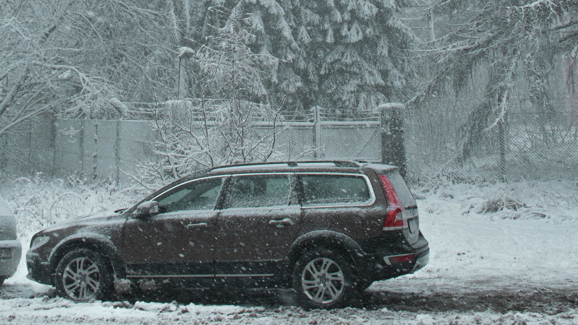 red car on road near trees covered with snow during daytime