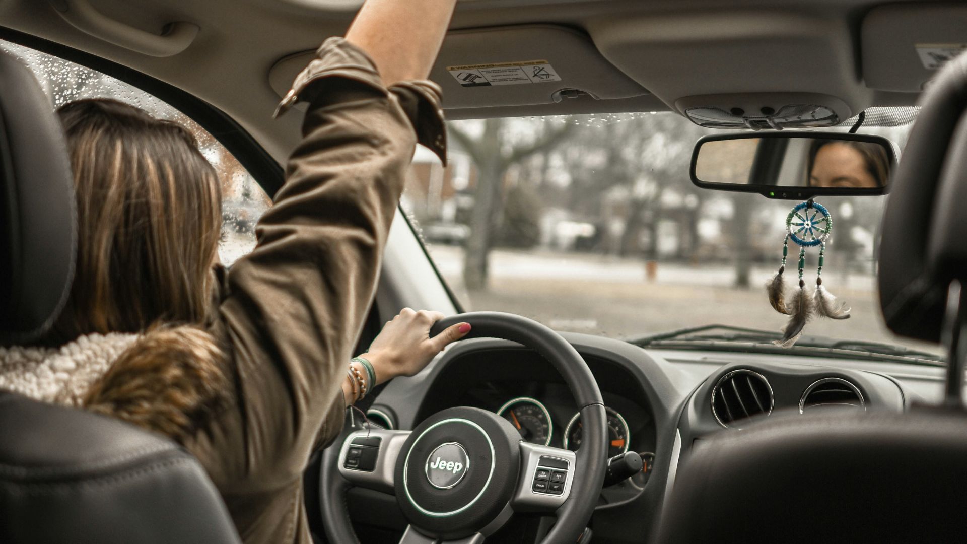 woman raising her right hand inside black and brown vehicle
