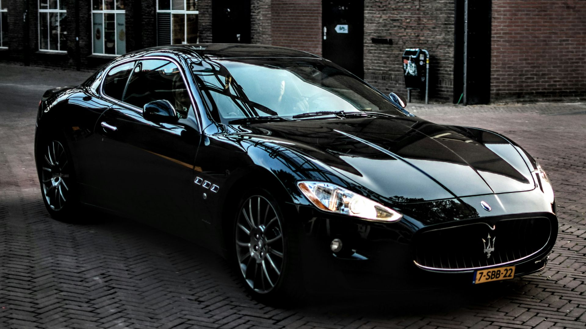 black porsche 911 parked in front of brown brick building