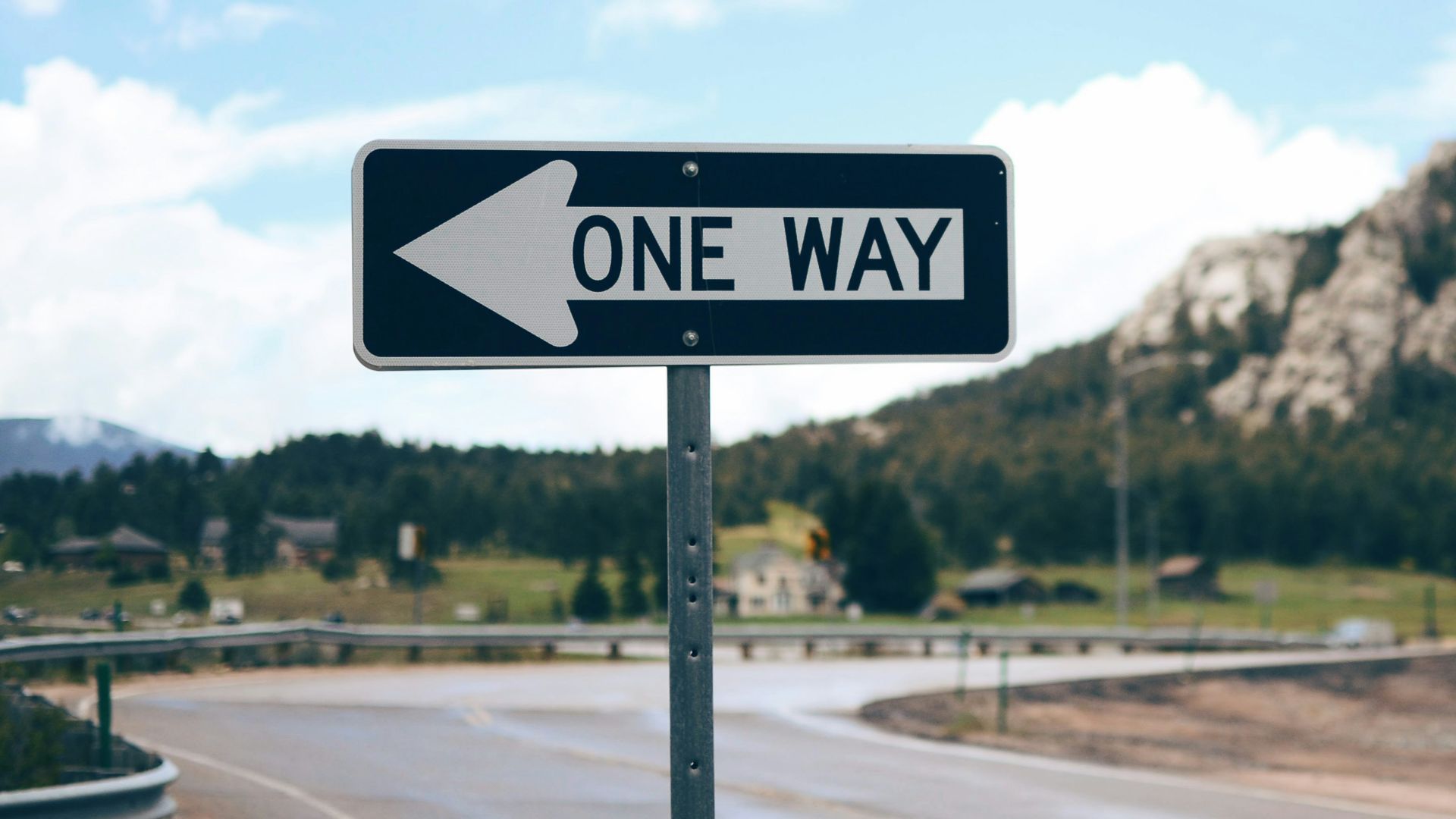 One Way street sign beside road far at the mountain during daytime