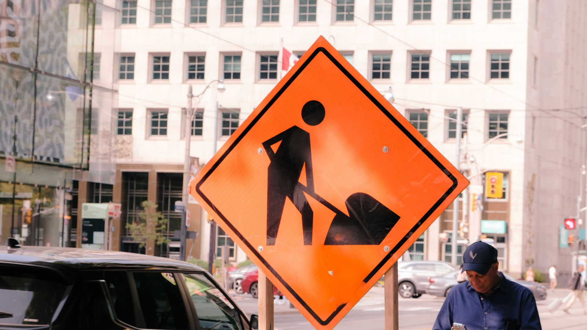 Orange construction sign with worker digging symbol and shovel