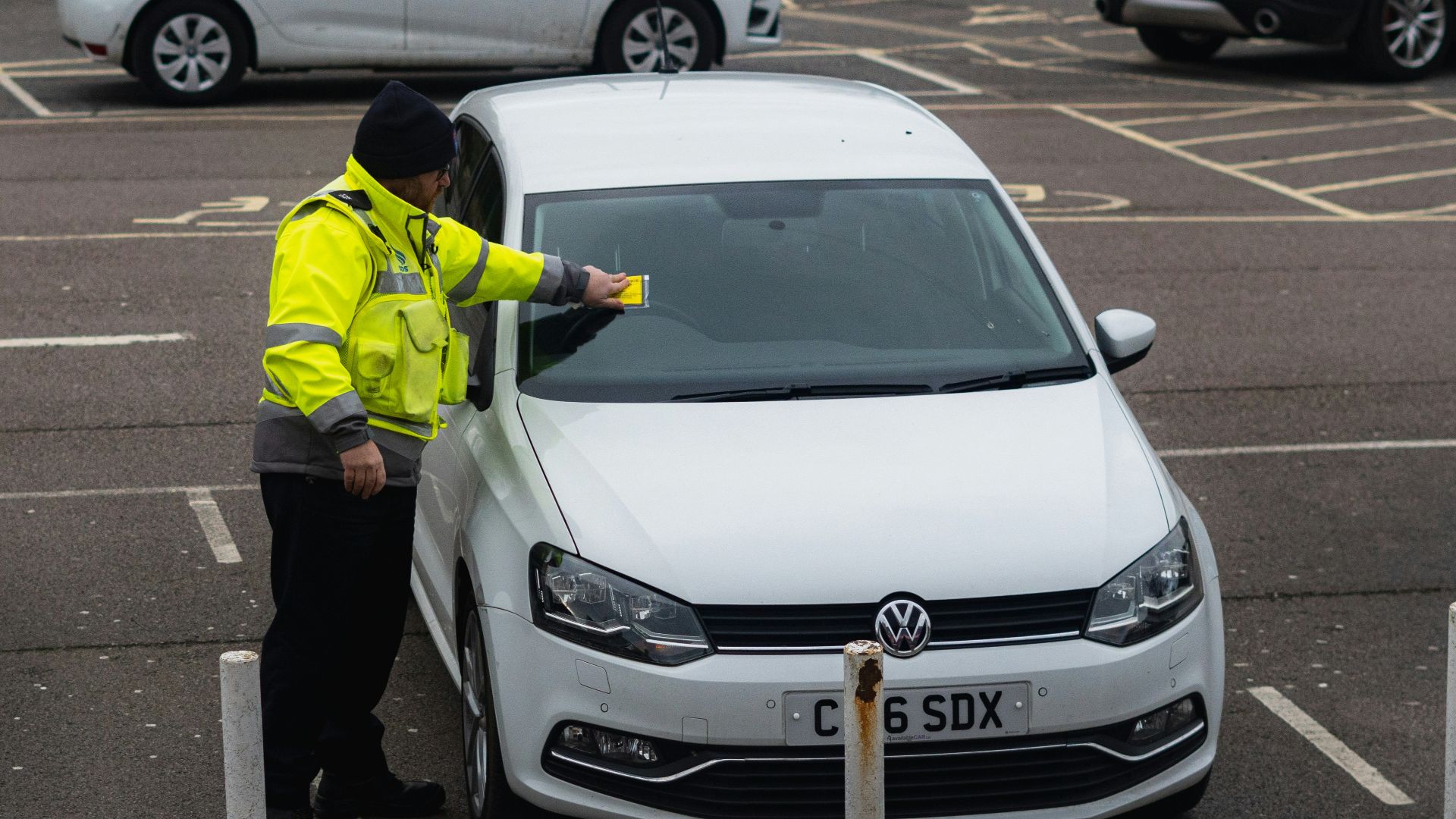man in yellow jacket standing beside white car