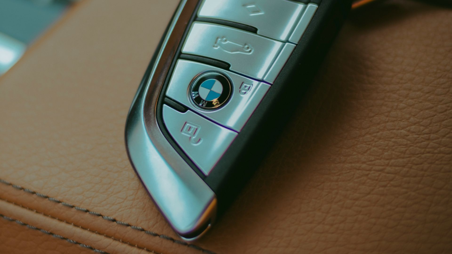 Two BMW car keys resting on leather seats.