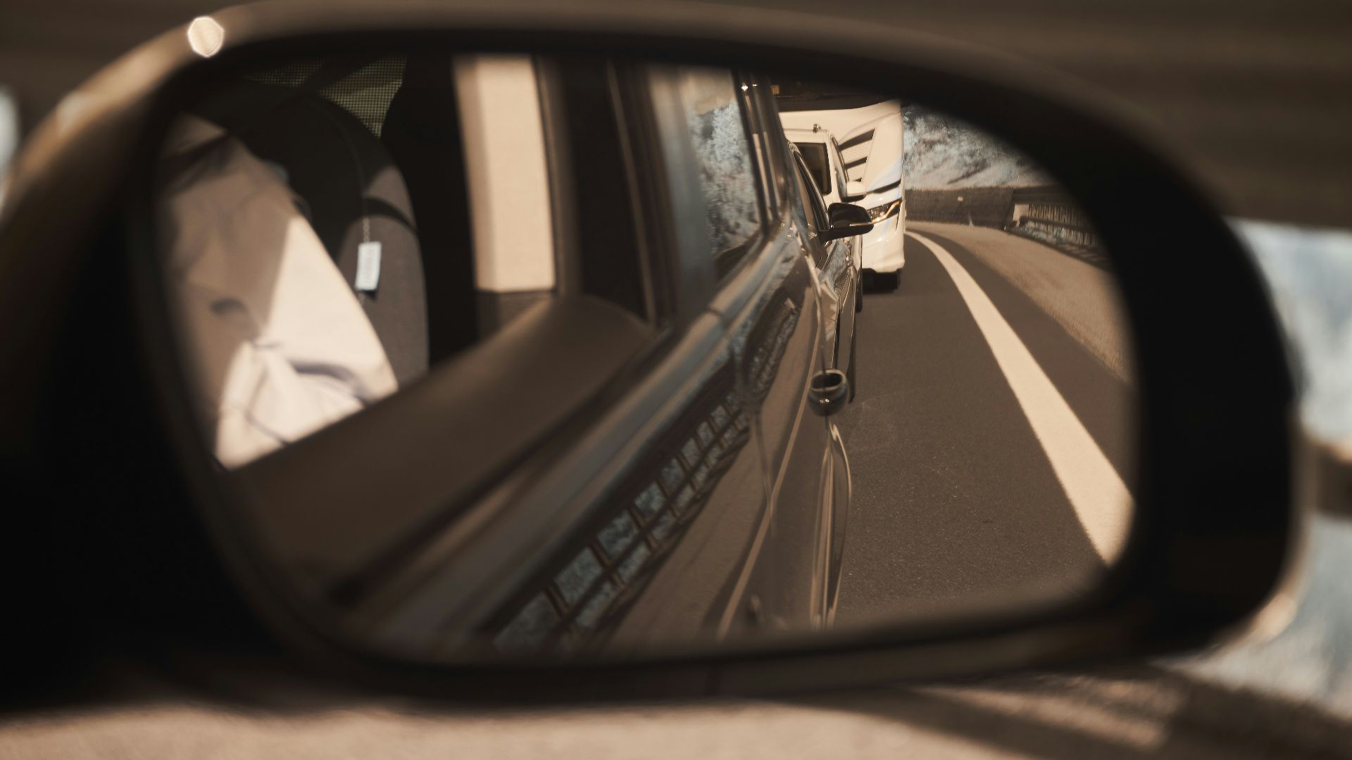 a car's side view mirror reflecting a truck on the road