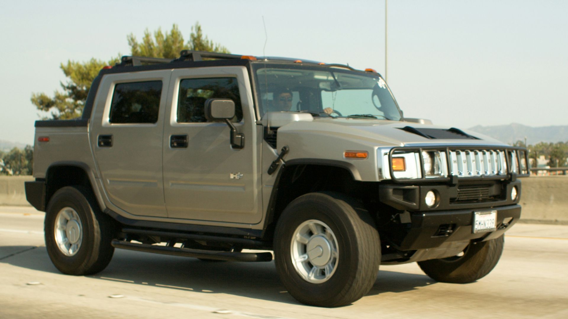 Gray hummer h2 truck driving on a highway.