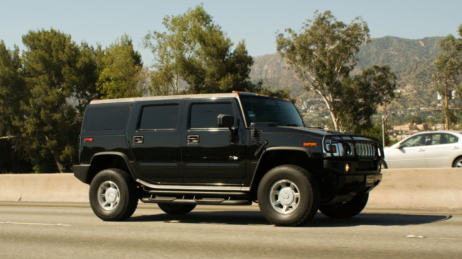 Black hummer h2 driving on a highway.