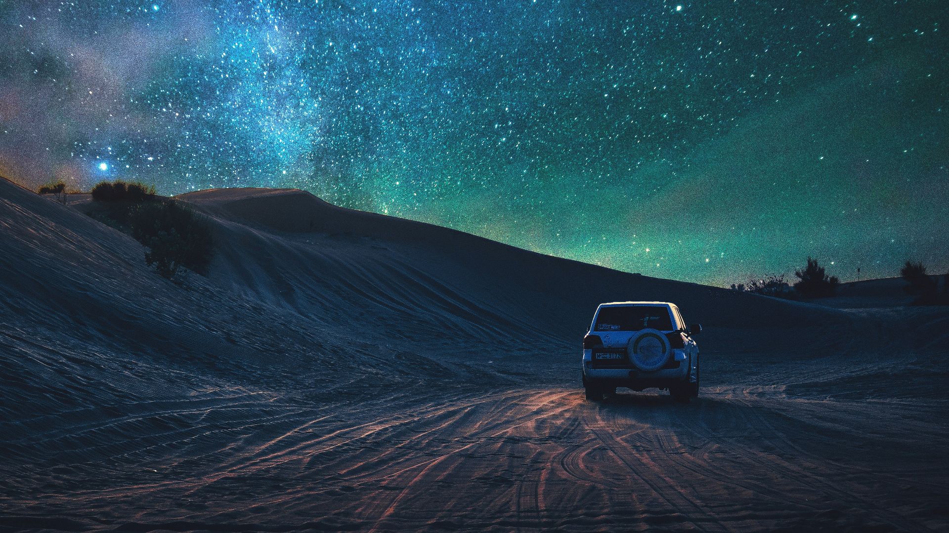 gray vehicle traveling on desert during nighttime