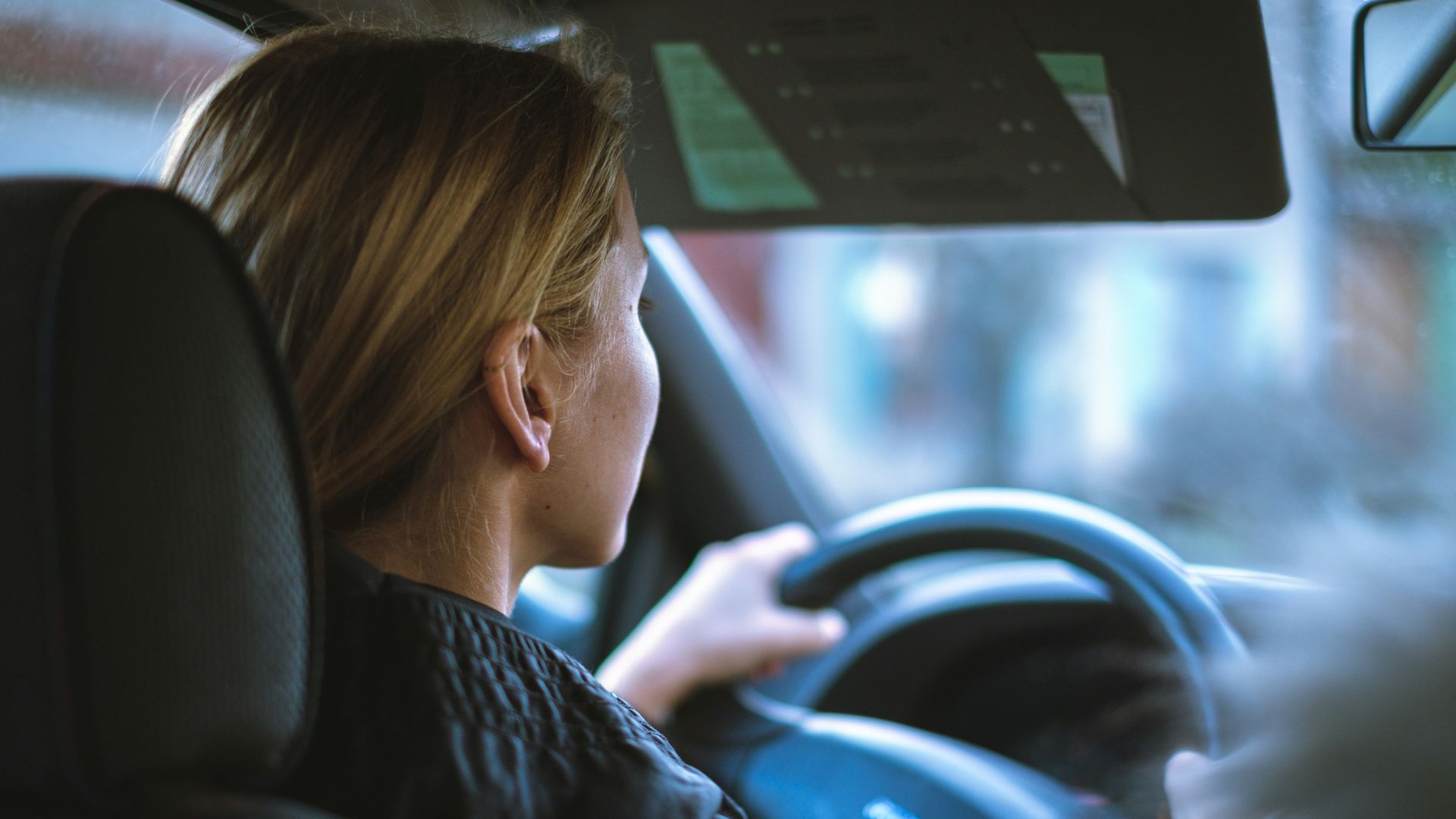 a woman sitting in a car with a steering wheel