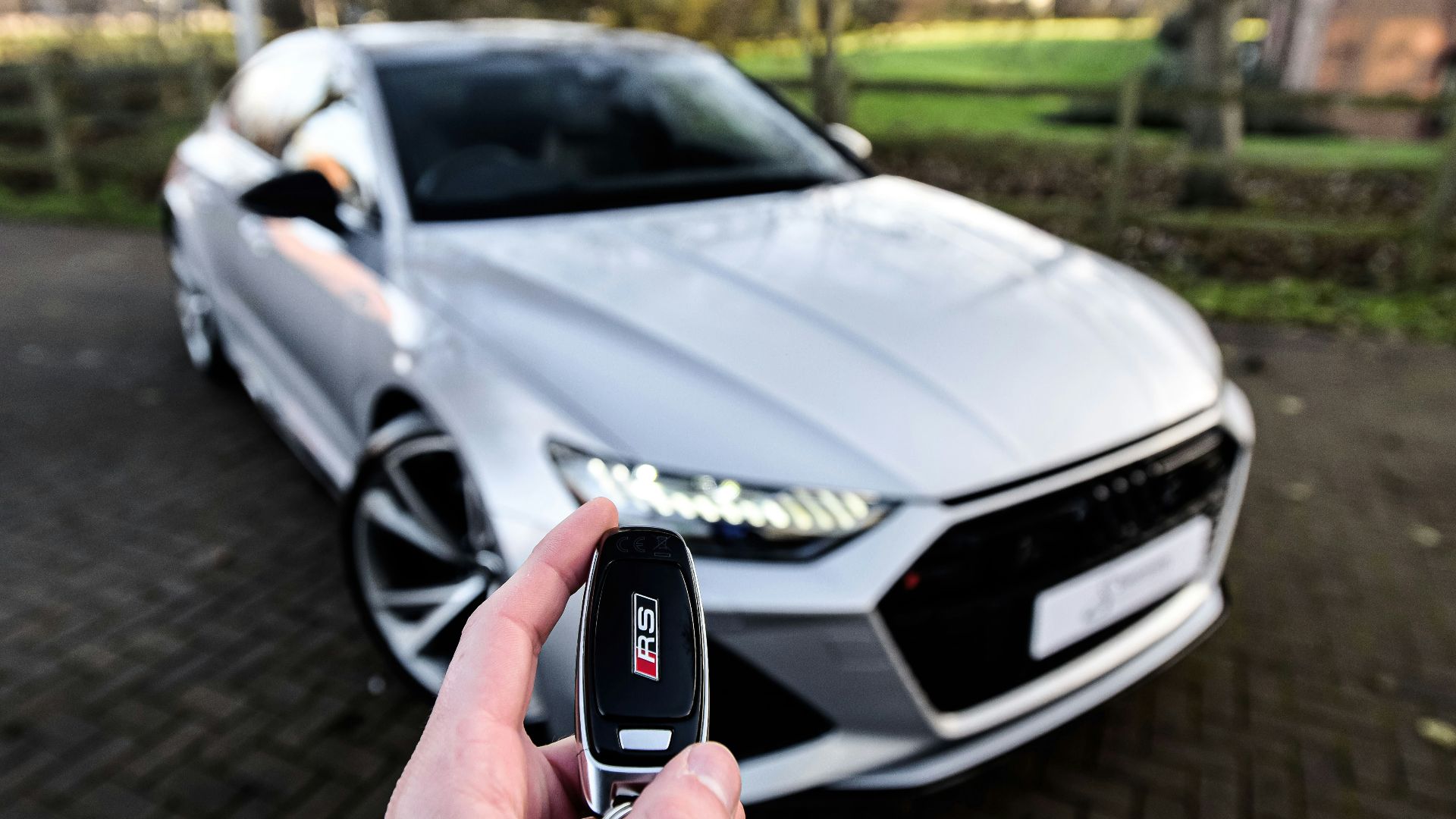 a person holding a car key in front of a silver car