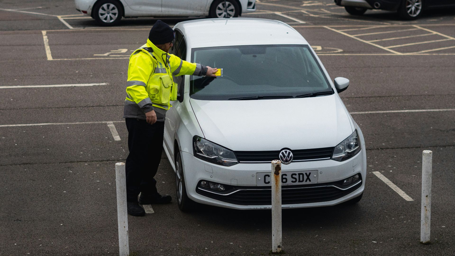 man in yellow jacket standing beside white car