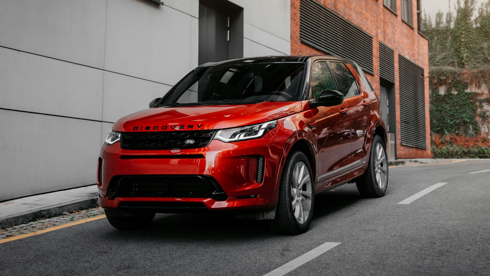 red car parked beside white concrete building during daytime