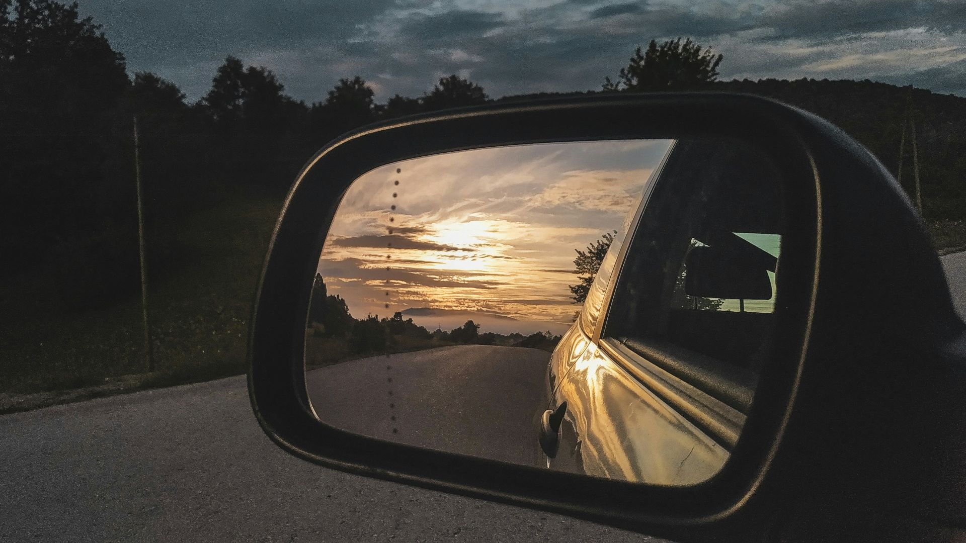 a rear view mirror on a car reflecting a sunset