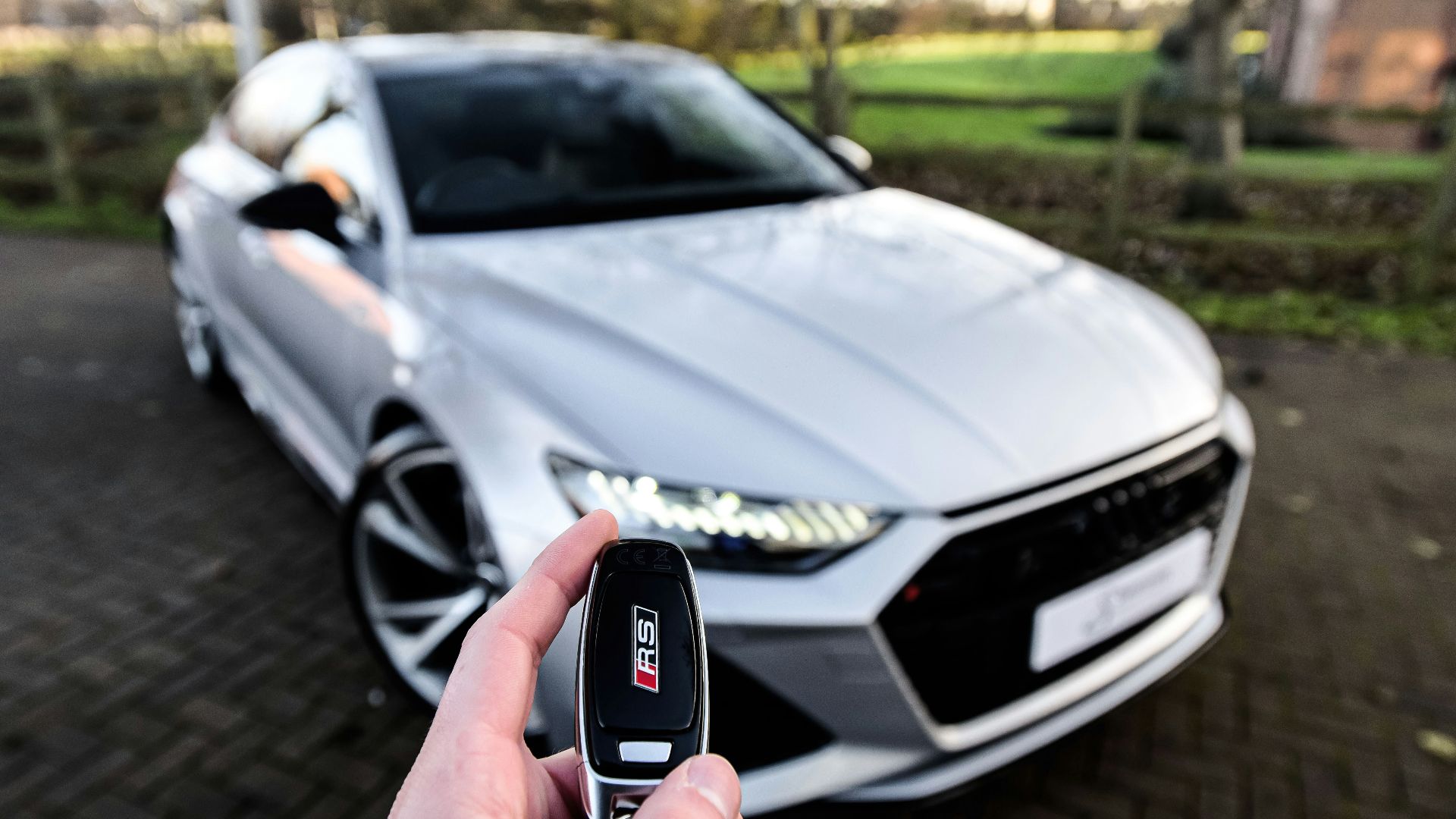 a person holding a car key in front of a silver car