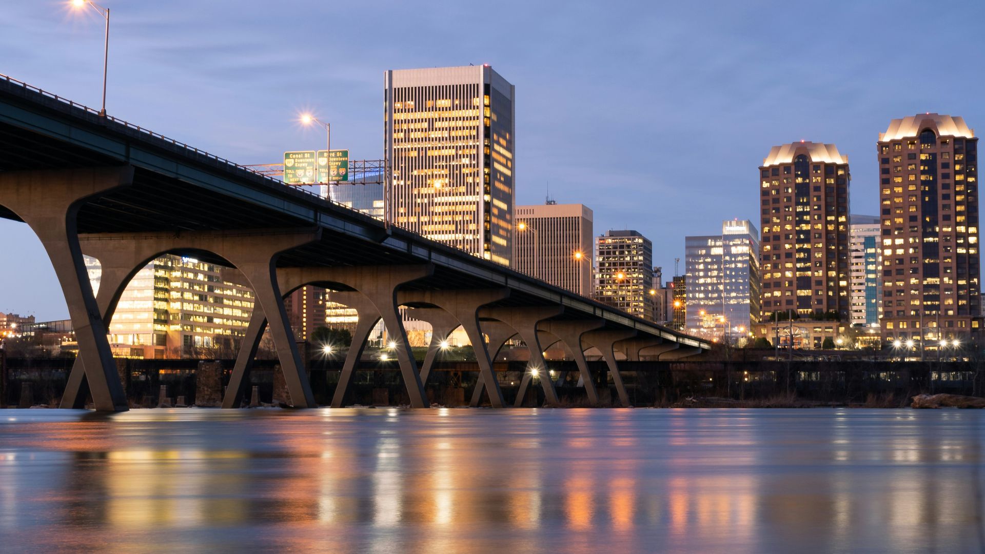 bridge over water near city buildings during night time